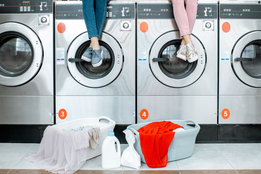 People sitting on top of a row of washing machines.